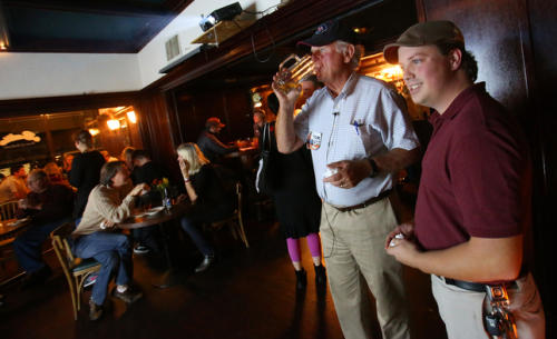Richmond mayoral candidate Tom Butt, second from right, sips a beer while watching early election results with supporter Jayson Fennimore, right, during an